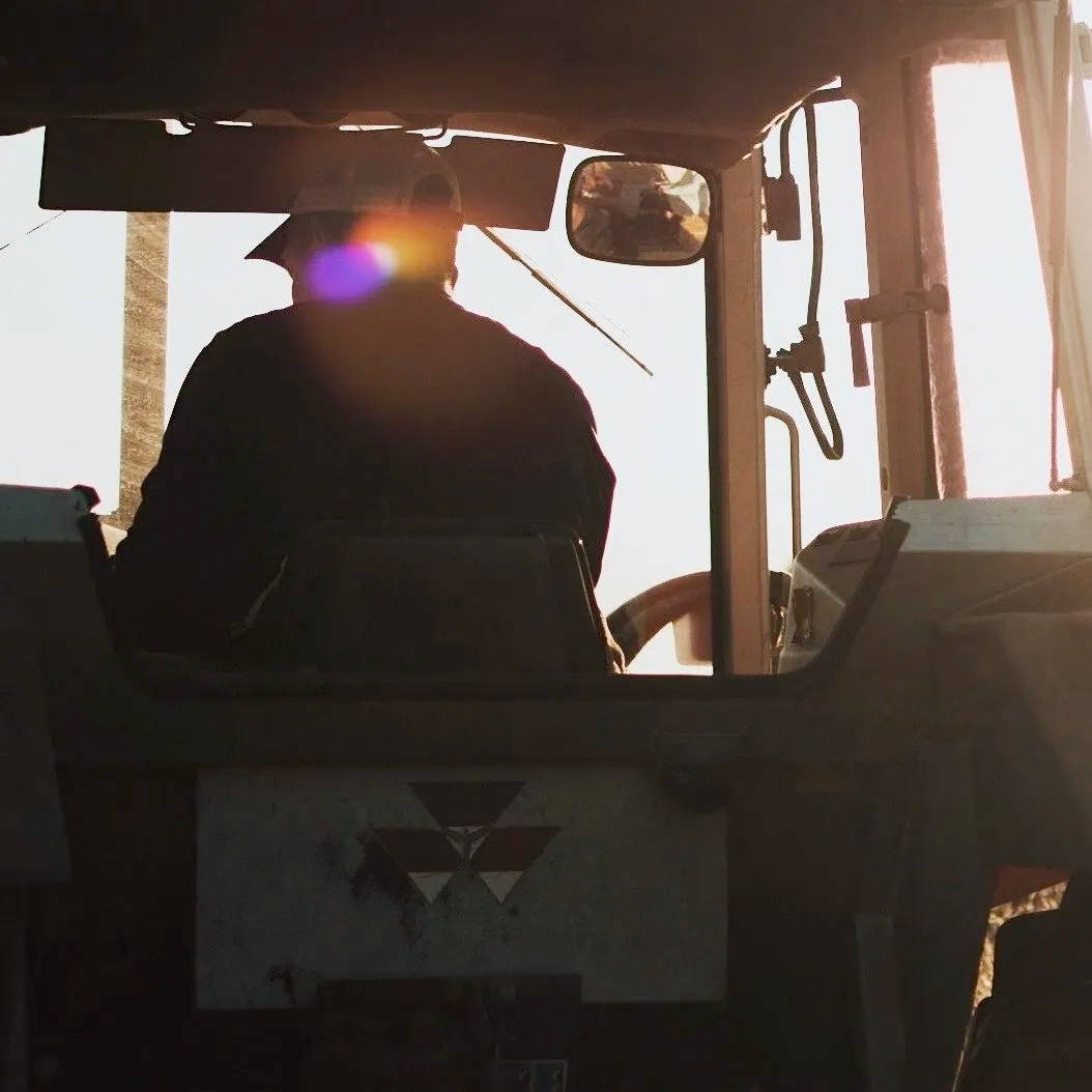 close up of a person in a tractor silhouetted agains the sky