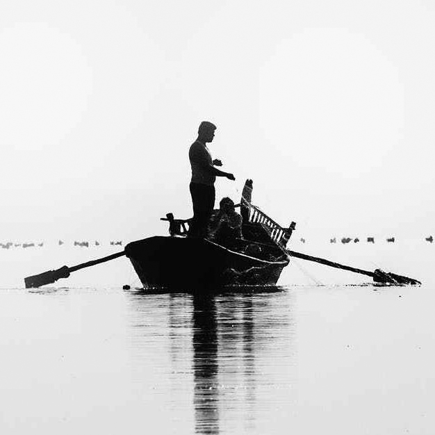 person standing in a rowboat holding a fishing net