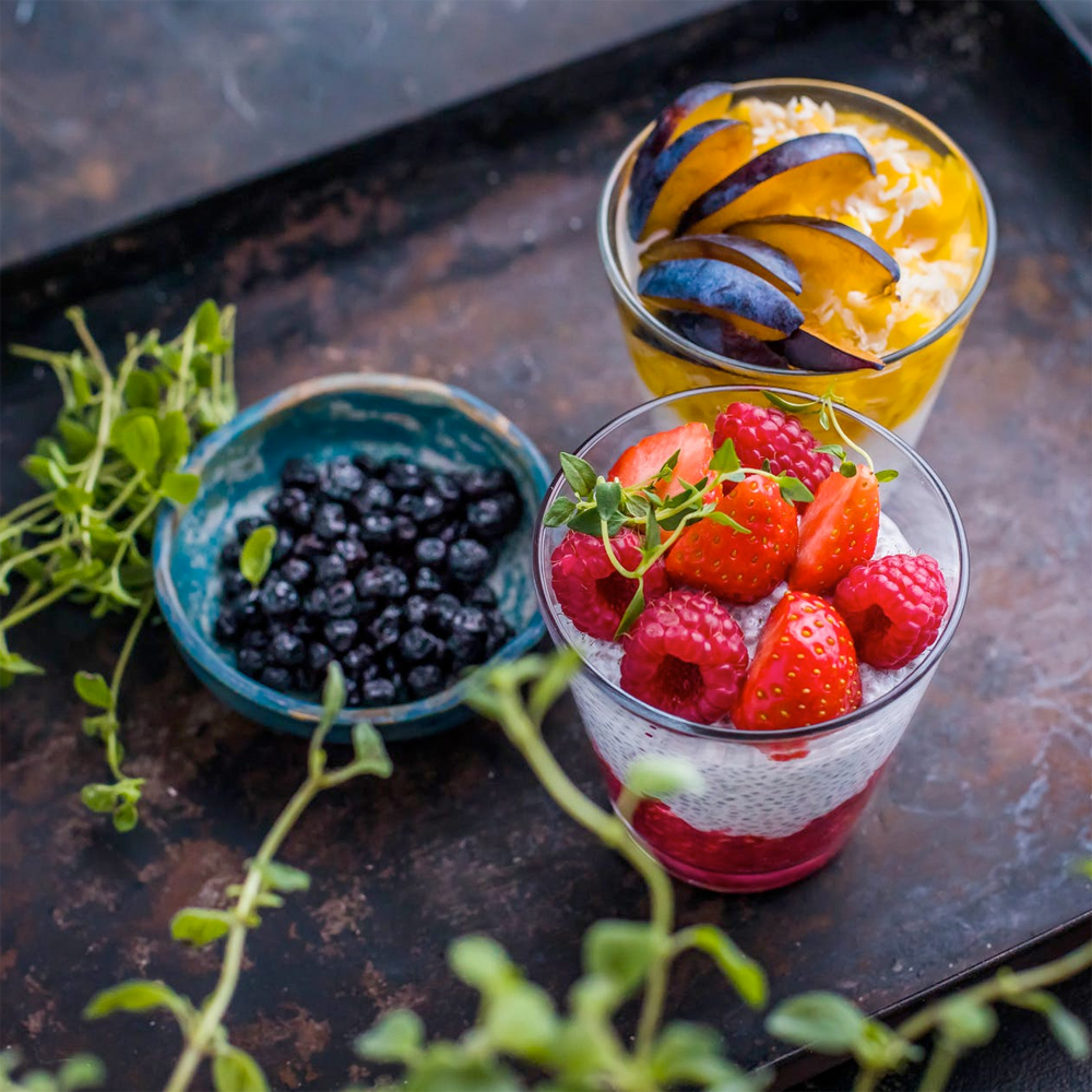 two glasses and a bowl filled with colourful fruit